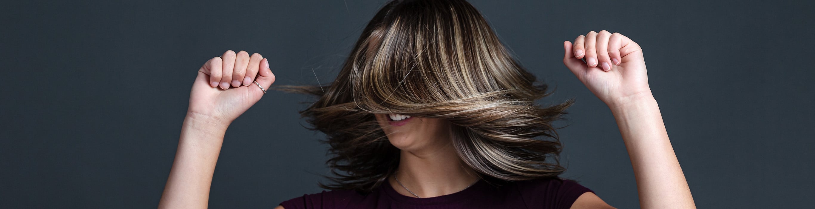 Woman with freshly coloured, healthy-looking hair, illustrating the results of correctly processing and rinsing permanent hair colour.